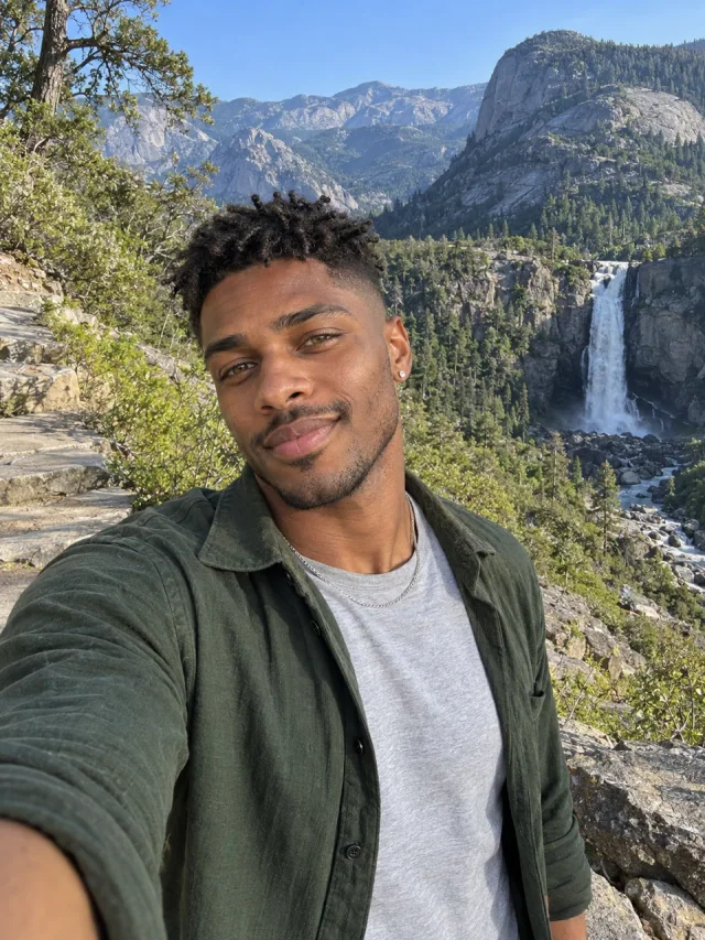 AI example of an adult Afro-Brazilian man in a green overshirt on a mountain trail